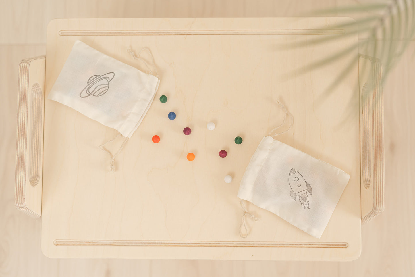 colorful wooden balls spilled out of canvas holding bag on a small child size wooden activity table