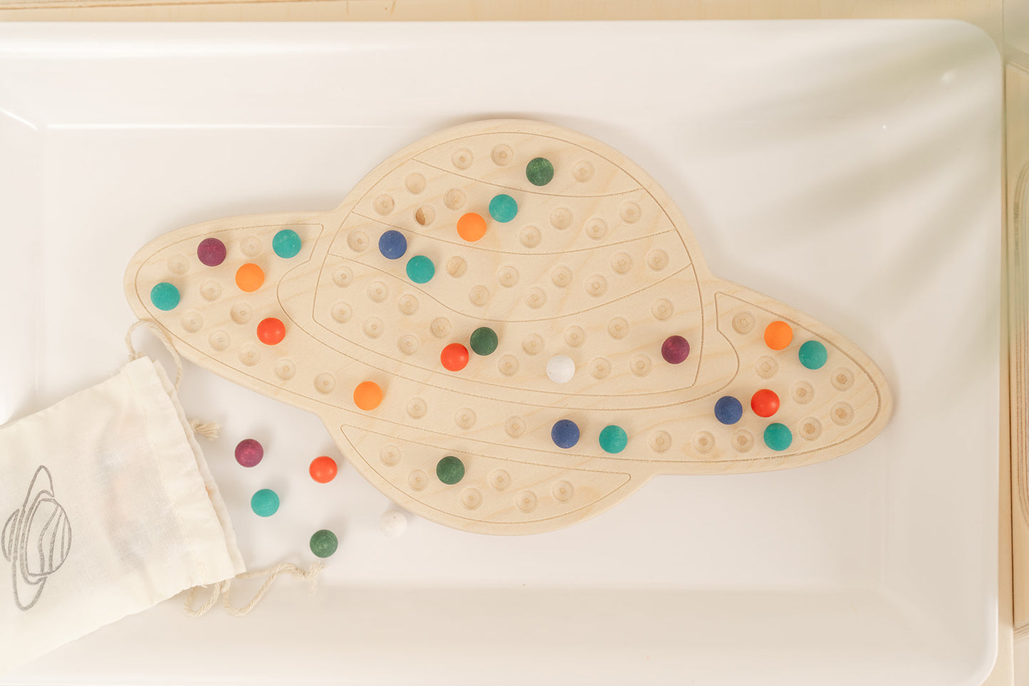 Montessori materials with wooden saturn board and colorful wooden balls to place in saturns shape and make endless designs. There is canvas bag to hold the 98 wooden balls and a bamboo tong in the bag for extra fine motor challenge.