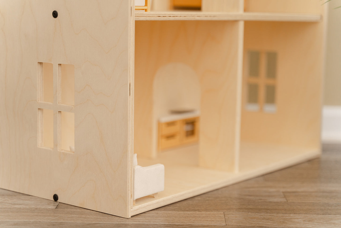 A modern wooden dollhouse with recessed windows and cutout doorframes