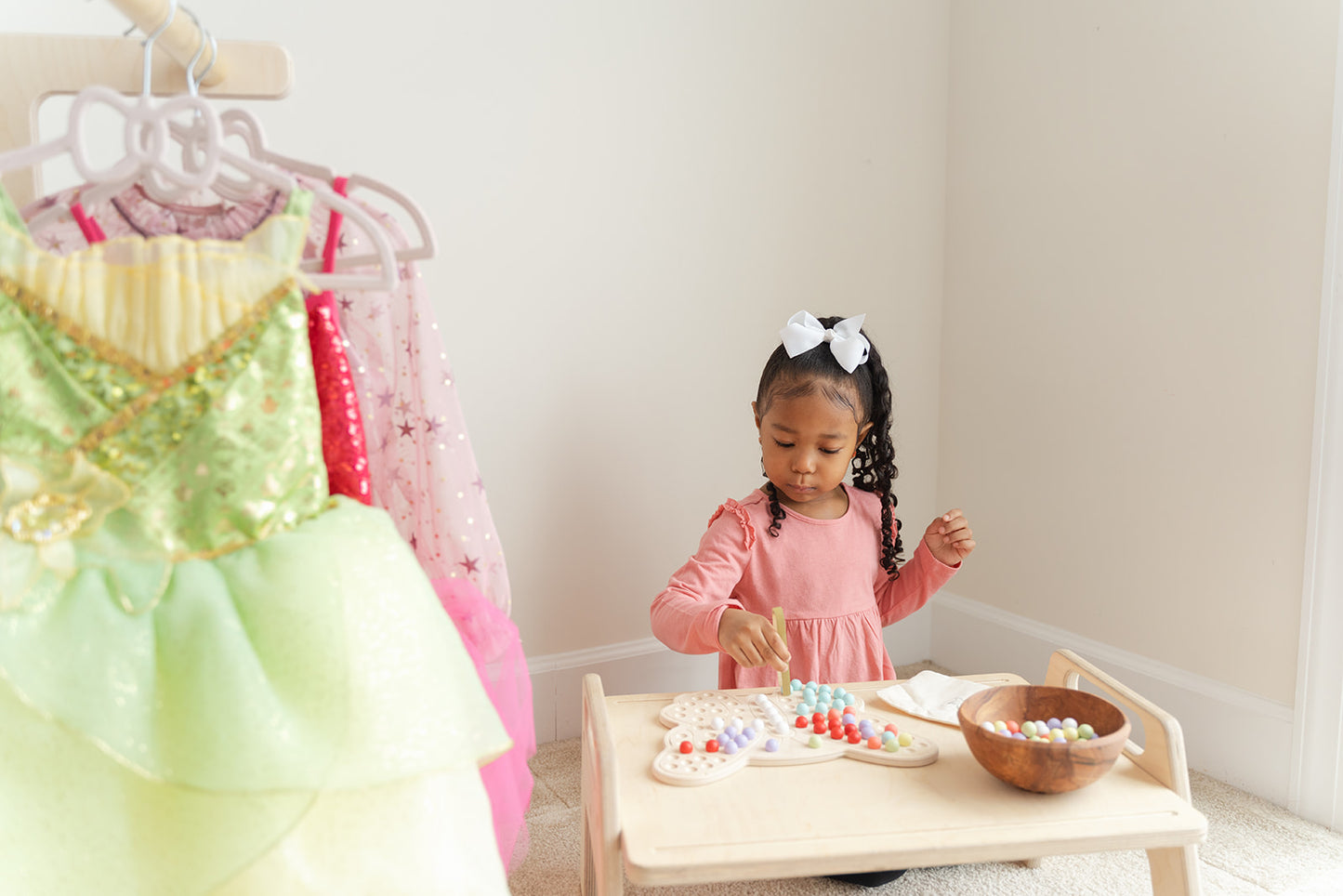 Preschooler sorting rainbow-colored wooden balls by color on butterfly Montessori activity board learning color recognition and categorization skills. Educational peg board toy for ages 3-6 promoting early math concepts through hands-on sorting matching and organizing activities. Wooden sensory toy encouraging logical thinking decision-making and cognitive development through open-ended color sorting games and creative play scenarios in screen-free learning environment.