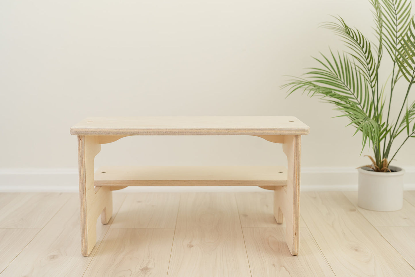 Close-up of quality wooden kids step stool showing smooth Baltic birch construction with rounded edges for toddler safety, Montessori kitchen helper with modern hardware and solid joinery handcrafted in USA, sturdy two-step learning stool featuring natural wood grain and eco-friendly non-toxic finish safe for children's daily use in kitchen and bathroom.