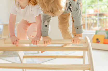 Blueberry and Third Pikler-style climbing arch with baby climbing toys nearby, natural wood arch supports crawling, pulling up, and gross motor milestones