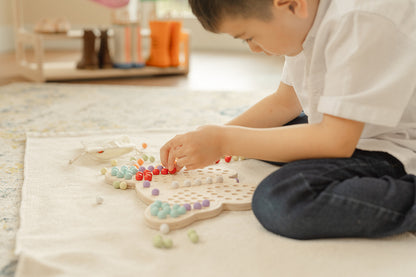 Two preschool children sharing wooden butterfly activity board during quiet independent play time demonstrating collaborative learning and turn-taking skills. Montessori peg board toy keeping kids ages 3-6 engaged and focused without screens. Calming sensory activity perfect for morning routine quiet time or transitions providing peaceful hands-on occupation while developing fine motor skills concentration and social interaction through shared educational play experience.