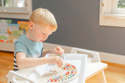 A kid playing with a rainbow shaped aactivity puzzle