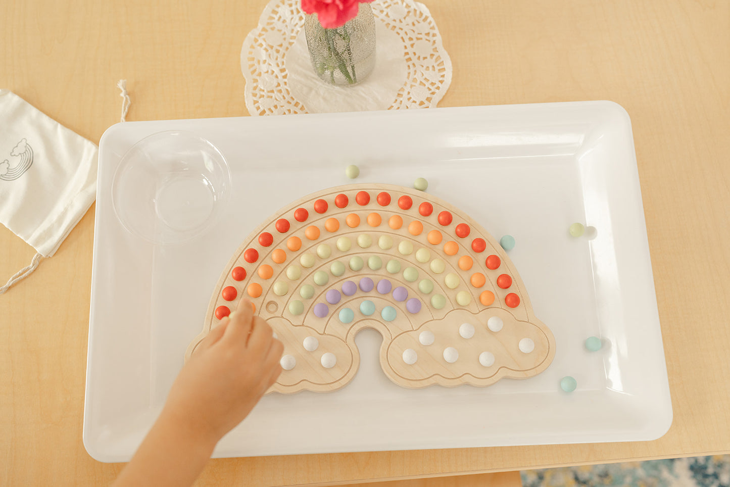 Montessori materials with wooden rainbow board and colorful wooden balls to place in rainbow shape and to make endless rainbow designs. There is canvas bag to hold the 140 wooden balls and bamboo tongs that are included.
