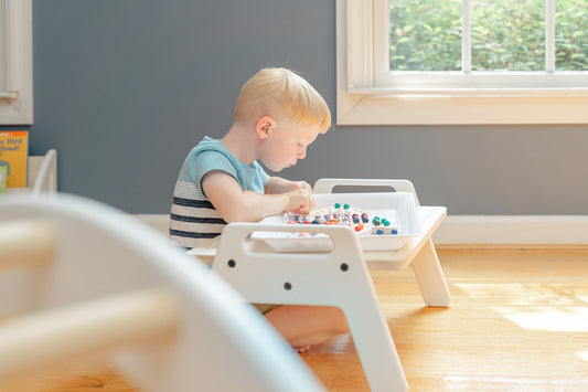 A child playing with a wooden toy on an activity tray in a bedroom