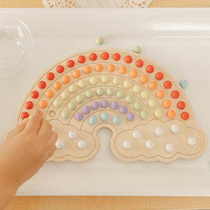 Montessori and Reggio inspired materials with wooden rainbow board and colorful wooden balls to place in rainbow shape and to make endless rainbow designs. There is canvas bag to hold the 140 wooden balls and bamboo tongs that are included.