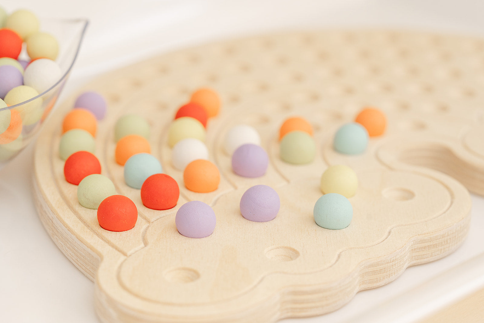 Rainbow shaped activity board with bright painted wooden balls
