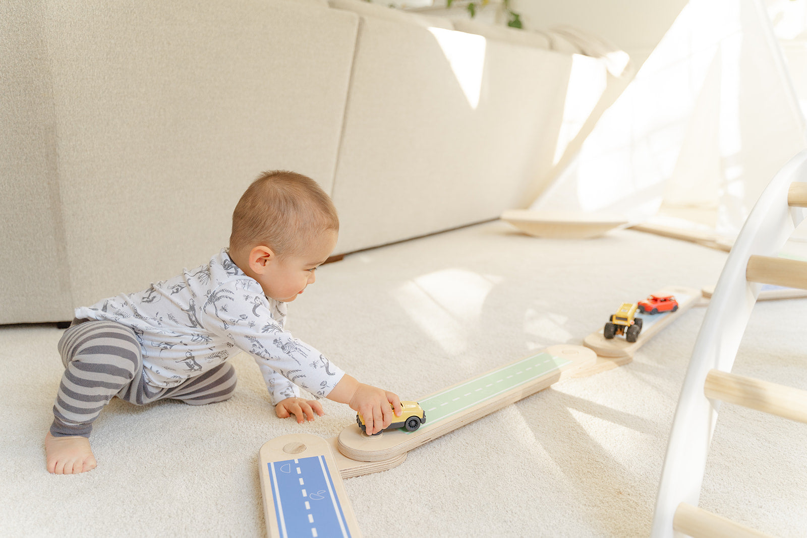 A baby playing with trucks on top of a balance beam