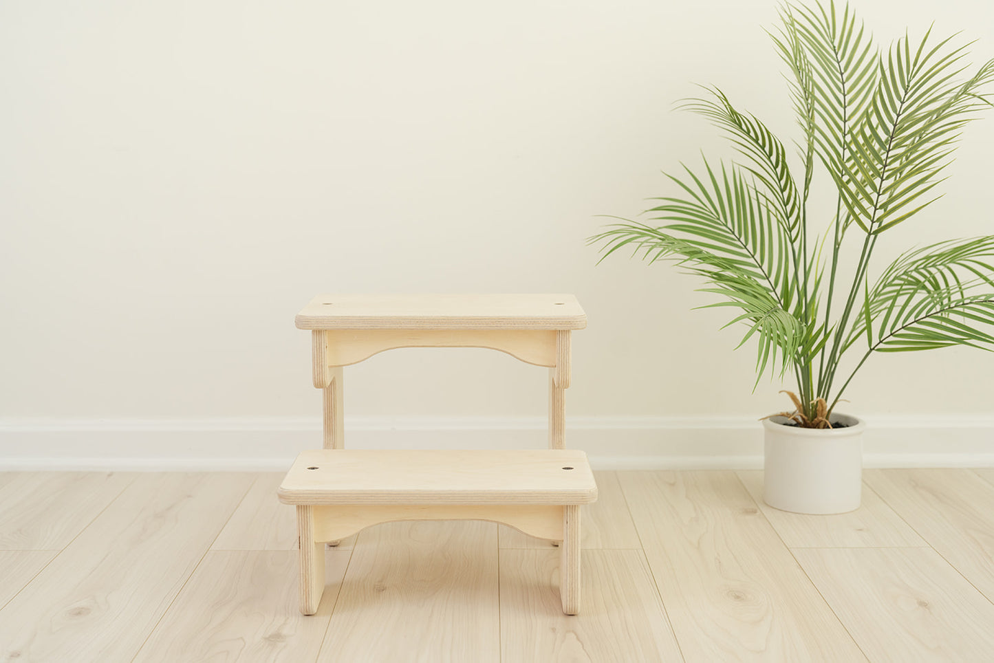 Overhead view of wooden toddler step stool showing smooth sanded birch top step with spacious standing platform, kids step stool with non-slip surface for safe footing during bathroom and kitchen activities, two-step stool featuring modern minimalist design with quality craftsmanship, compact stepping stool for reaching sinks counters and high shelves.