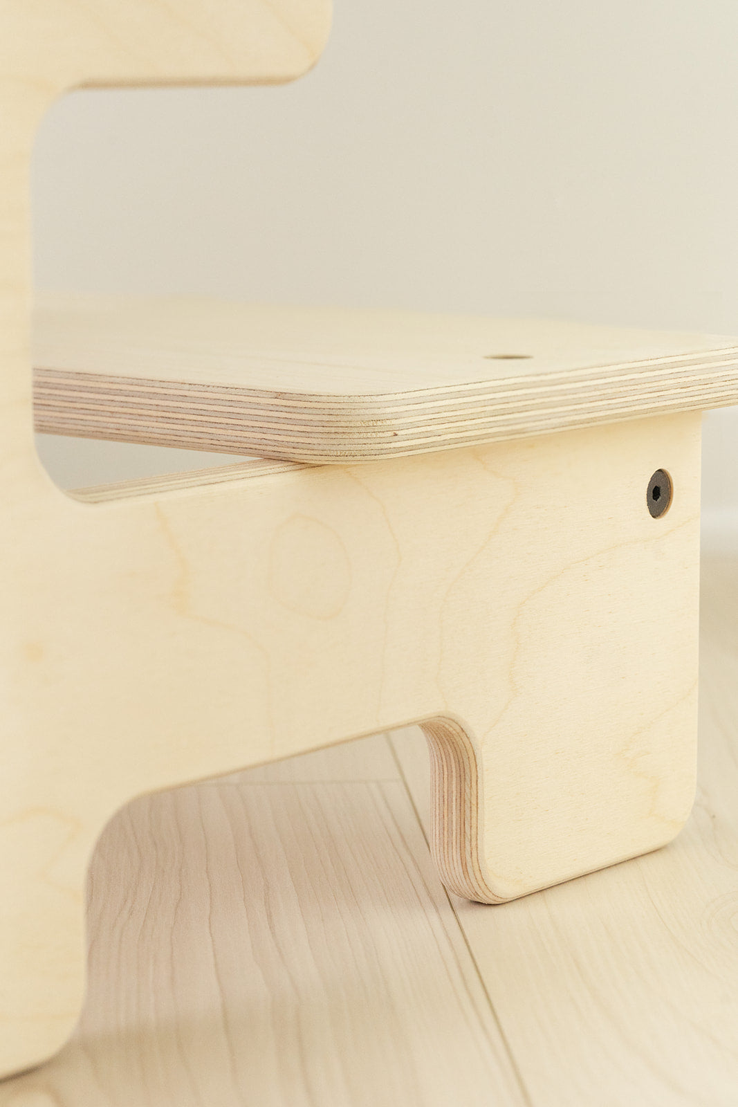 Quality wooden toddler step stool detail showing hand-sanded Baltic birch construction with rounded edges for child safety, close-up of kids helper stool featuring eco-friendly non-toxic water-based finish and sturdy joinery, Montessori children's step stool handcrafted in USA with modern hardware exceeding CPSC safety standards supporting 200 pounds, natural birch kitchen bathroom step stool dimensions 22.5"W x 12"H x 15"D for ages 3 through preschool.