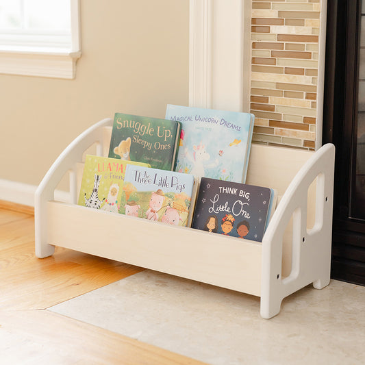A bookshelf next to a fireplace, placed on the ground for easy access for children