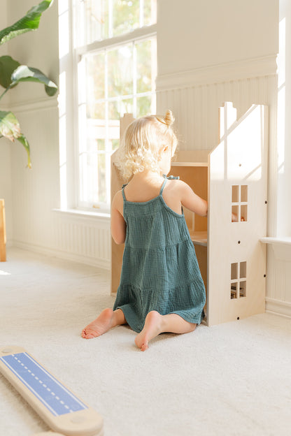 Child playing with large wooden dollhouse during pretend play arranging miniature furniture and creating stories together, 3-story life-size doll house spacious enough for multiple kids to play simultaneously fostering social skills cooperation and turn-taking, wooden playhouse encouraging sibling play playdates and group activities while developing communication skills empathy and shared imaginative scenarios for ages 3-10 years