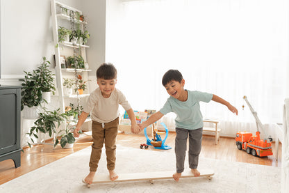 Multiple toddlers rocking together on wooden wobble beam developing social play turn-taking . Preschool balance board encouraging cooperative gross motor play vestibular stimulation and coordination development for young children. Open-ended play furniture supporting multiple body positions sitting standing rocking for sensory seeking kids ages 18 months to 6 years building confidence balance and physical awareness through dynamic tilting motion in playroom classroom setting