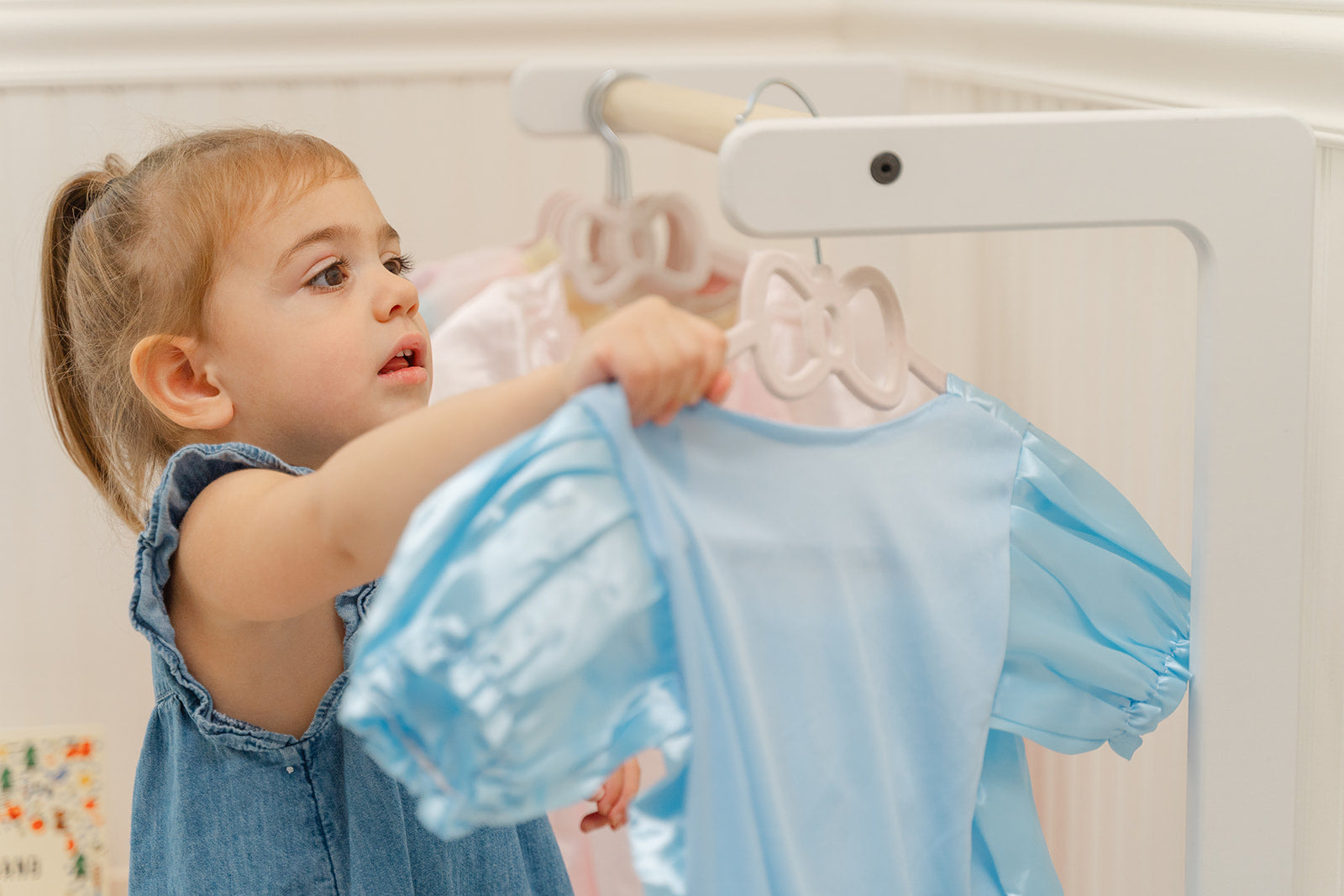 A child picking out a costume from a child-size clothing rack.
