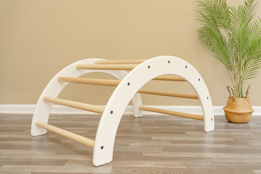Climbing arch placed on a wood floor with white paint and natural wood handles