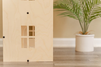 Side profile of a wood dollhouse with modern black hardware and decorative windows
