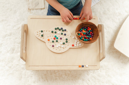Child creating imaginative design with colorful wooden pegs on Saturn activity board showcasing unlimited pattern-making possibilities for ages 3-8. Educational space-themed peg board encouraging artistic creativity problem-solving and critical thinking through open-ended STEM play. Montessori learning toy with no right or wrong way to play fostering confidence experimentation and creative exploration through hands-on tactile manipulation in screen-free educational play environment perfect for elementary st