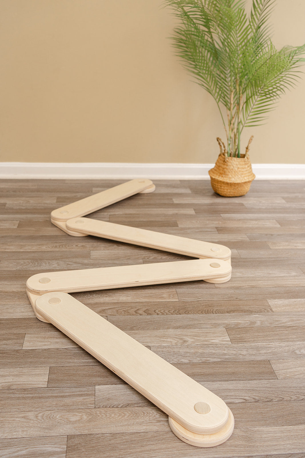 Kids balance beam in zigzag configuration demonstrating modular design for endless play possibilities, wooden obstacle course toy with connectable beams creating custom shapes for imaginative play and coordination development in playroom