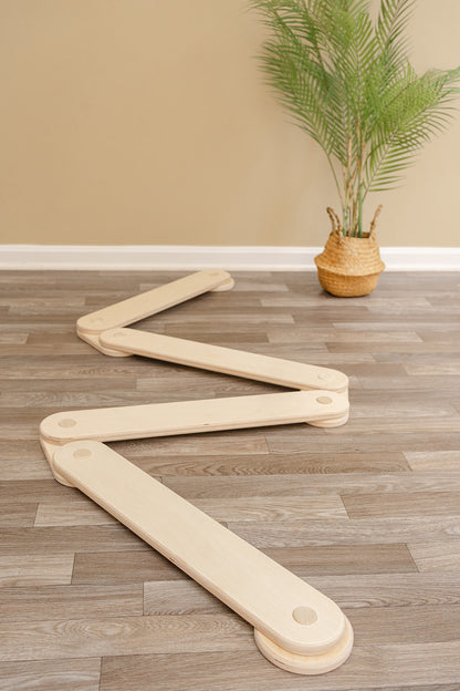 Kids balance beam in zigzag configuration demonstrating modular design for endless play possibilities, wooden obstacle course toy with connectable beams creating custom shapes for imaginative play and coordination development in playroom