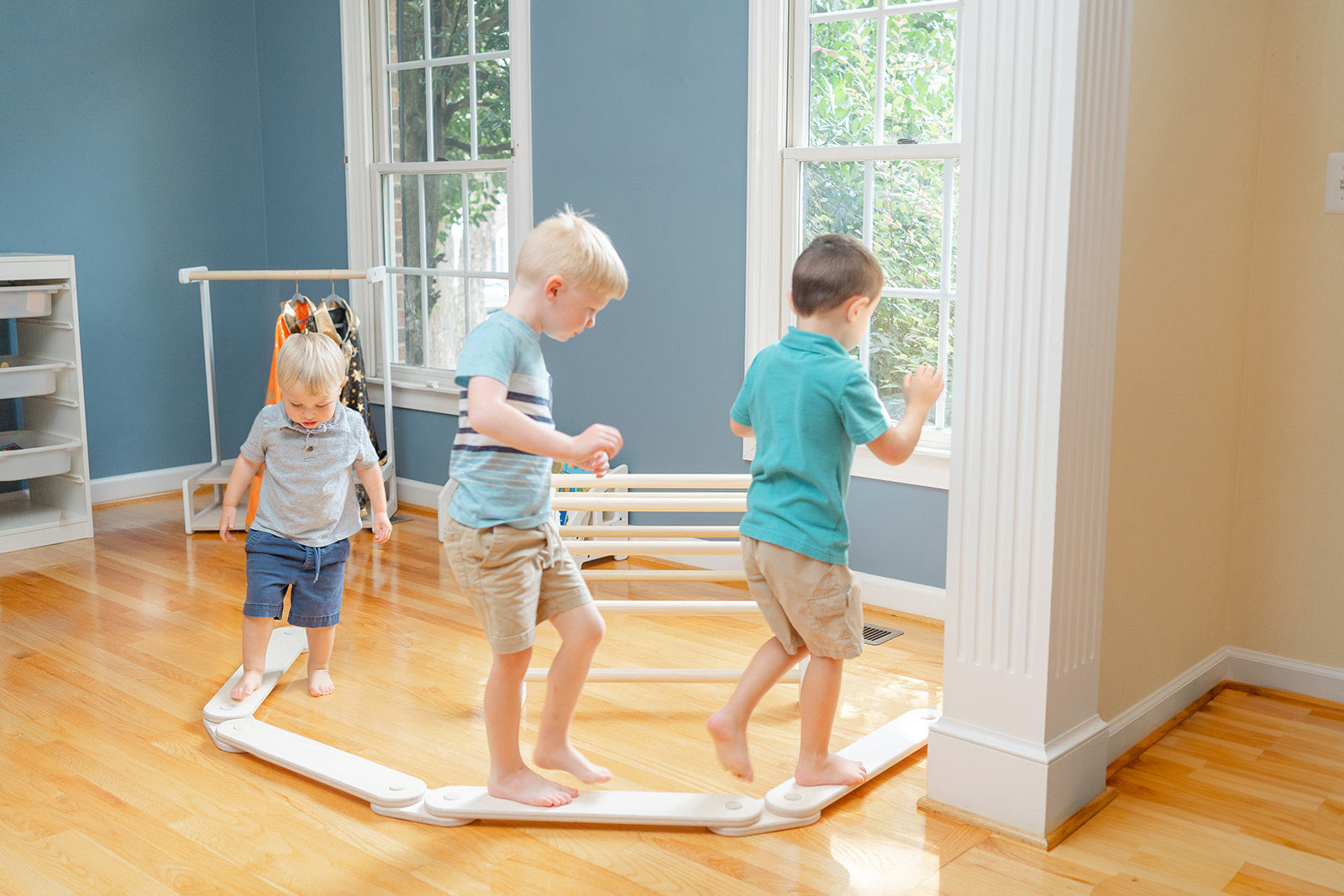 Modular wooden balance beam styled in modern minimalist playroom with neutral decor, Montessori-inspired gross motor toy blending beautifully with home furniture while providing active play opportunities for toddlers to develop balance coordination and physical confidence