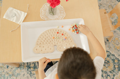 Preschool child engaged in fine motor skills development using wooden rainbow peg board placing colorful balls into holes, Montessori activity board promoting hand-eye coordination concentration and independent play for ages 3-6 years, sensory toy encouraging open-ended creative exploration and problem-solving through tactile manipulation, wooden educational toy providing screen-free quiet time activity perfect for keeping young kids busy and focused during independent play sessions