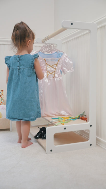 little girl playing with costumes on a kids clothing rack with shelves