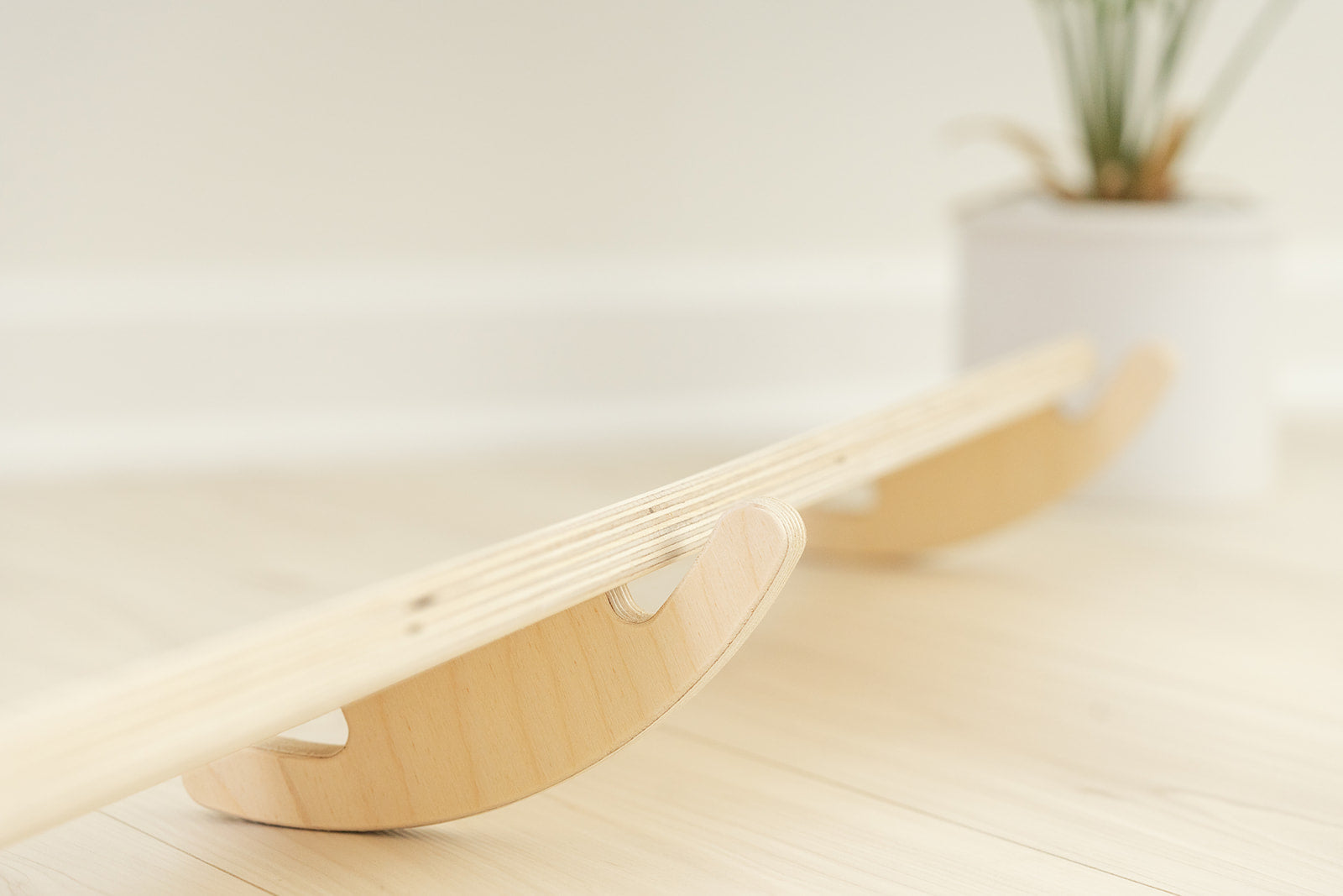 Side view of Preschool wobble beam showing curved base design for unique tilting balance challenge developing toddler gross motor skills. Wooden play furniture with smooth rocking motion stimulating vestibular system proprioception and body awareness for sensory processing development. USA-made birch plywood construction with non-toxic finish safe for young children exploring balance coordination and spatial orientation through open-ended active play experiences perfect for home or classroom environments.