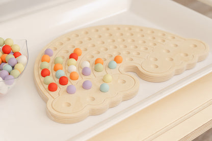 Creative pattern design made with colorful balls on wooden rainbow activity board demonstrating open-ended play possibilities, Montessori sensory board encouraging children to create unique designs, educational peg board toy for ages 3-6 promoting STEM learning through hands-on pattern recognition and creative problem-solving in screen-free tactile play environment