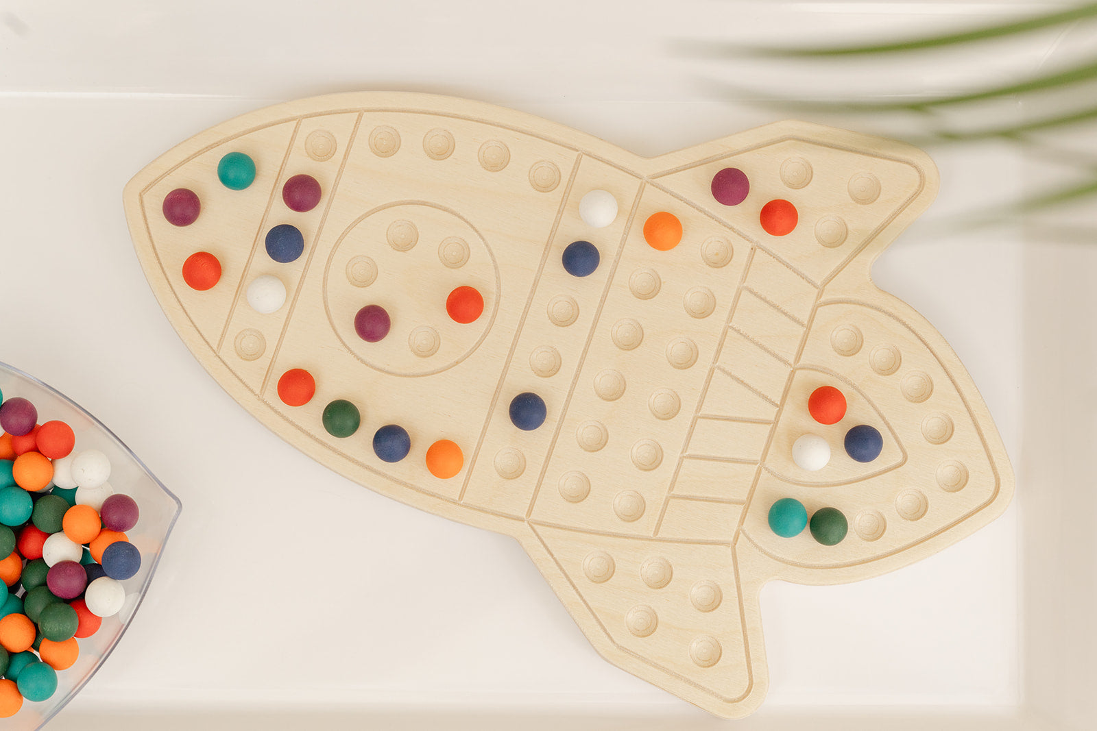 Rocketship activity board with colorful wooden balls for use by kids