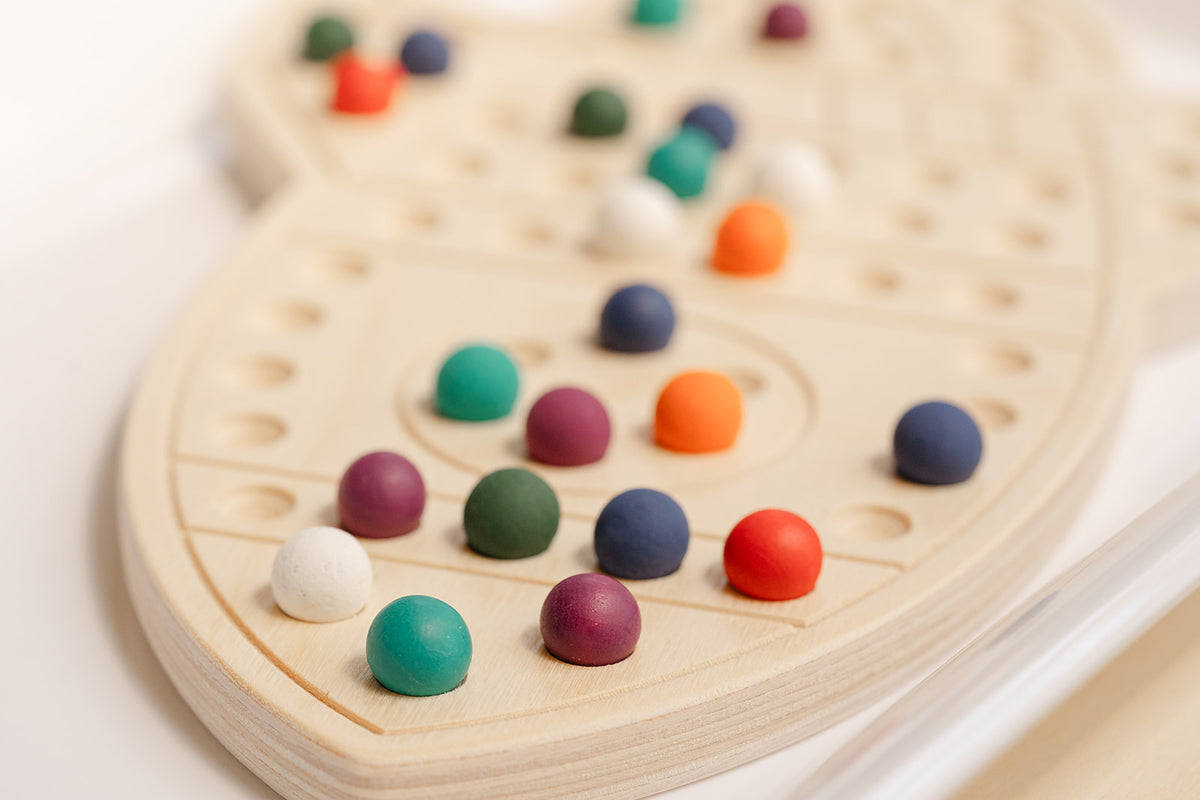 Close up picture of a rocket-shaped activity board with wooden colorful balls for peg board