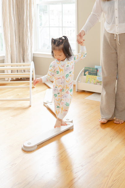 Toddler walking on wooden balance beam developing balance and coordination through Montessori-inspired open-ended play, child practicing gross motor skills on low-to-ground modular balance toy safe for ages 1-8 years