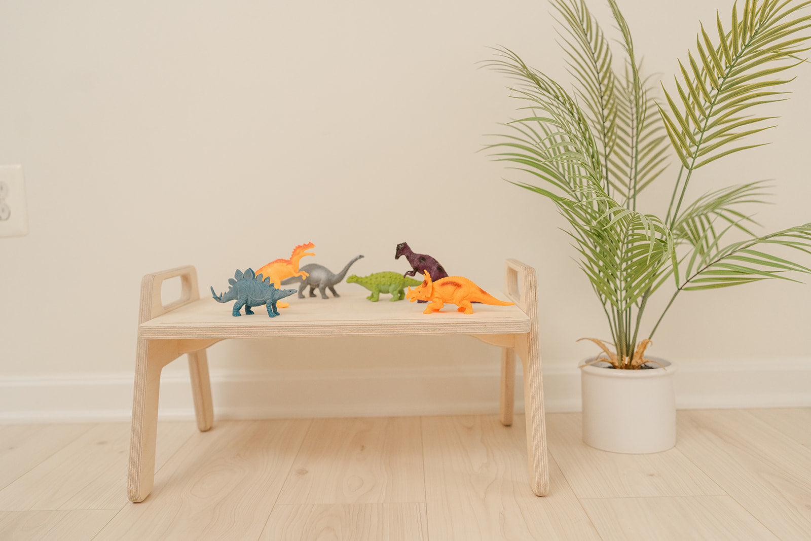 Parent easily moving portable wooden toddler table from room to room demonstrating lightweight mobile design, compact play tray perfect for small spaces apartments and multi-room use, Montessori floor table with convenient size allowing toddlers to have dedicated activity space anywhere in home for crafts sensory play or snacks