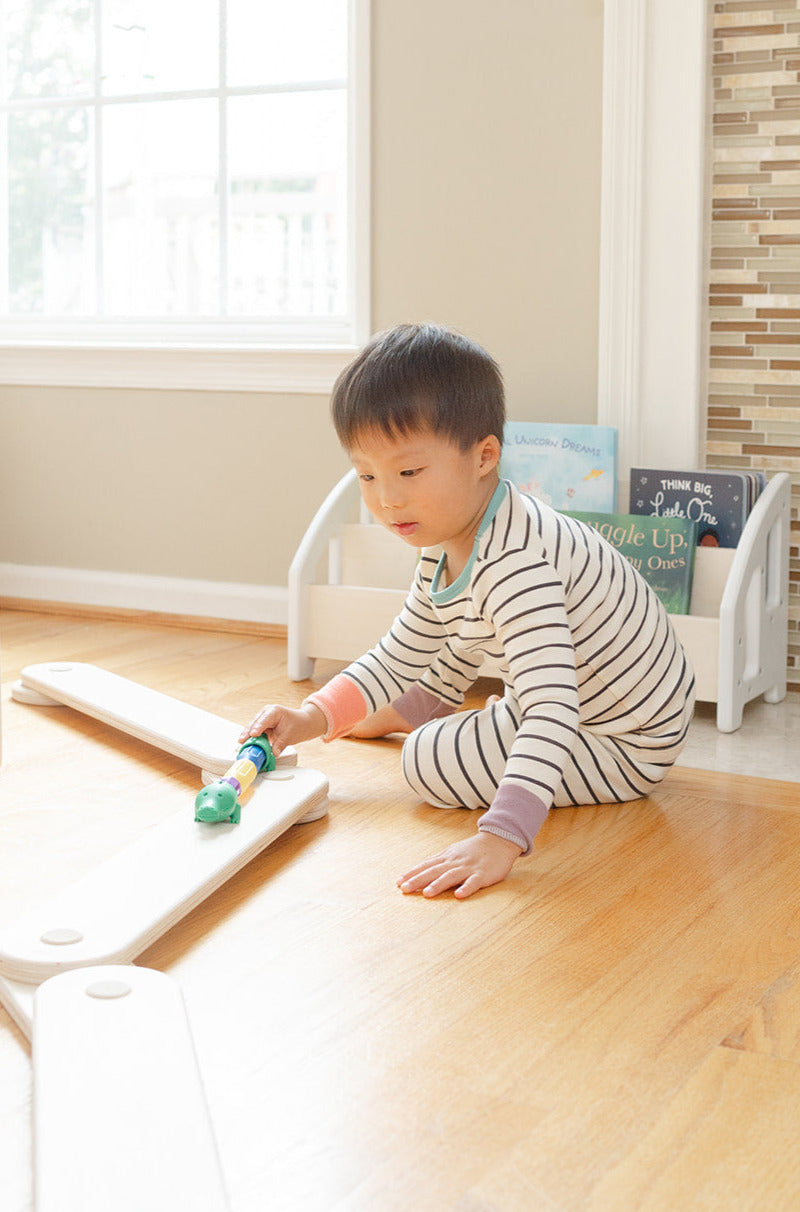 Child playing with a toy on a wooden balance beam