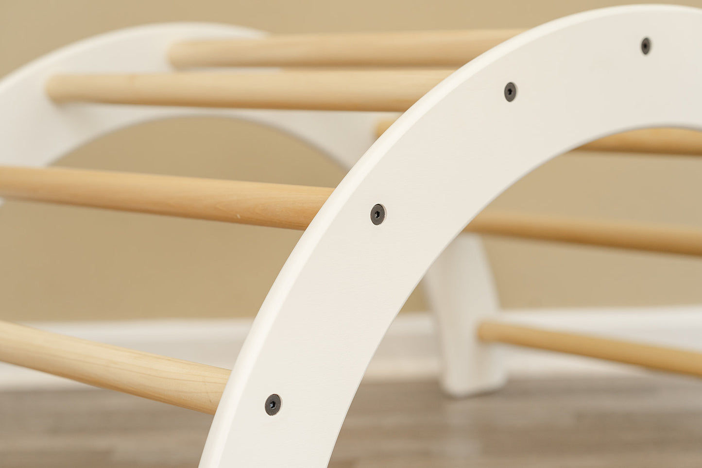 White climbing arch for kids with natural wood handles and black hardware.