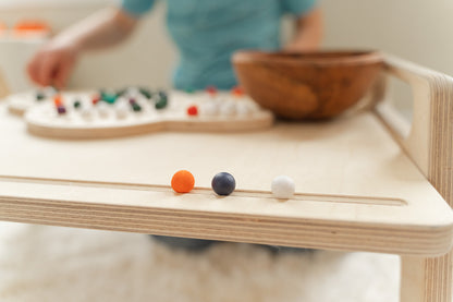 Close-up of USA-made wooden toddler table showing quality birch plywood construction with rounded edges and eco-friendly water-based finish, sturdy play tray featuring support beam for durability and stability, handcrafted Montessori furniture with smooth surfaces safe for children ages 18 months and up exceeding CPSC safety standards