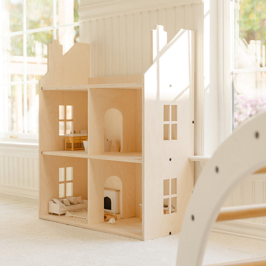 Wooden dollhouse set alongside a window in a playspace