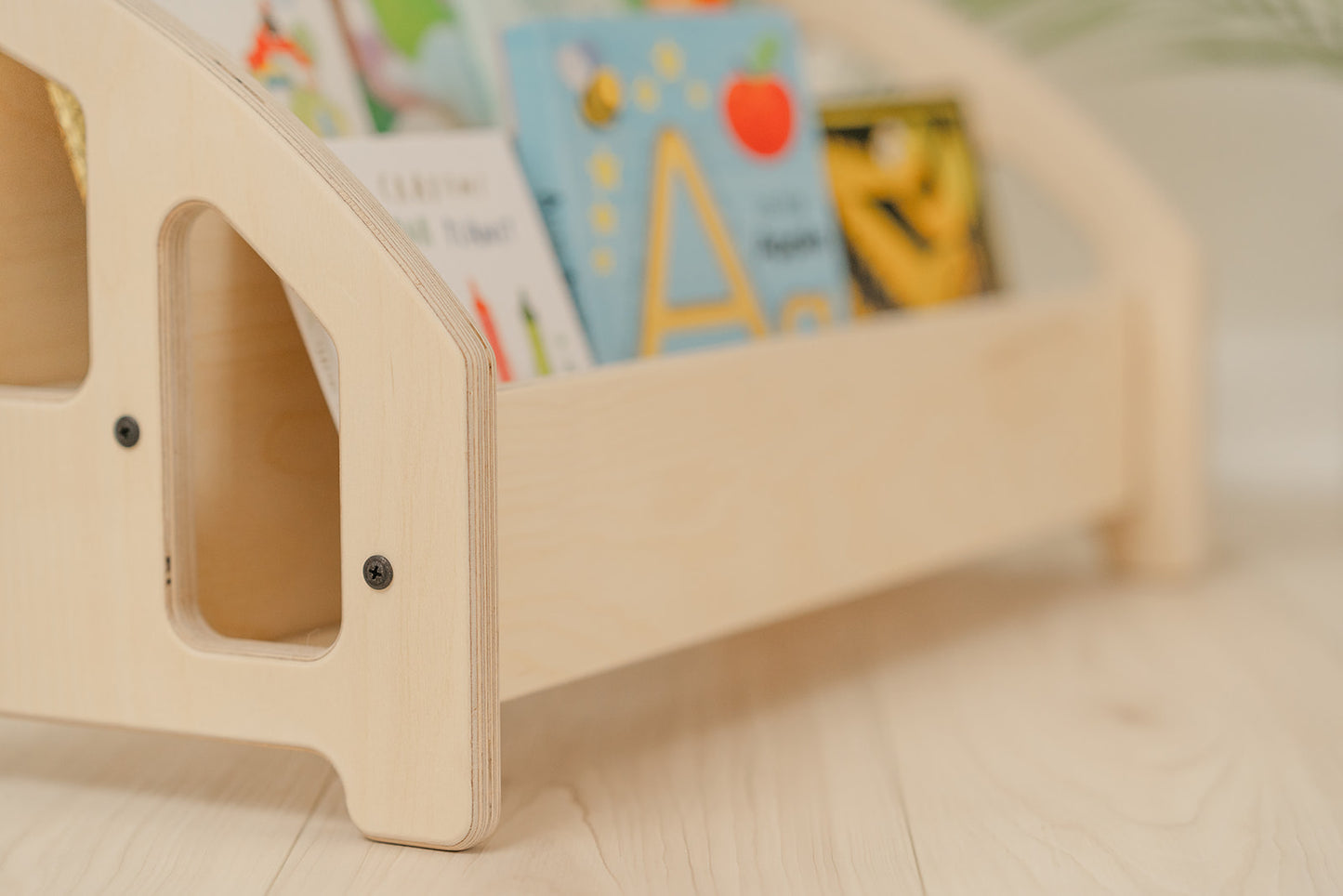 Close up view of quality wooden kids bookshelf showcasing two-tier front-facing book display shelf construction with rounded edges and beautiful smooth  finish safe for babies and toddlers, compact low-profile children's bookshelf measuring 12 inches tall by 24 inches wide fitting perfectly in nursery bedroom or playroom corner without overwhelming small spaces