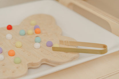 Close-up of USA-made wooden butterfly activity board showing quality Baltic Birch plywood construction with smooth finish and precisely drilled peg holes. Handcrafted Montessori educational toy with vibrant non-toxic water-based paint on wooden balls safe for children ages 3 and up. Durable sensory board featuring sturdy frame and carefully sanded edges exceeding CPSC safety standards designed for years of active preschool play and fine motor development.